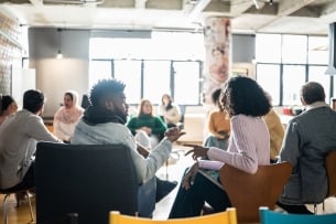 Two students talk to one another in a larger group setting