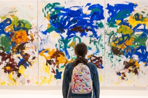 A person stands before a colorful Joan Mitchell painting in a Paris gallery