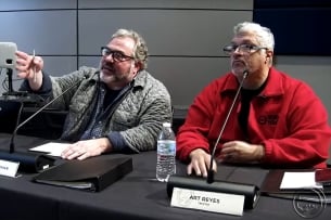 Mott Community College board members Michael Freeman and Art Reyes sit behind a desk, gesticulating, at a November board meeting.