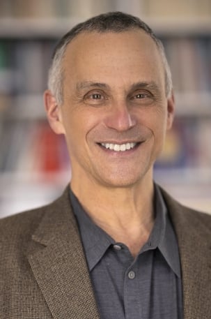 A headshot of Michael Roth smiling in a gray suit