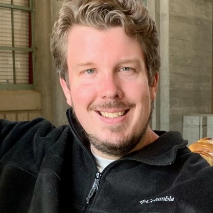 Marc Watkins, a light-skinned man with short brown and gray curly hair and a goatee and mustache, wearing a black zip-up fleece