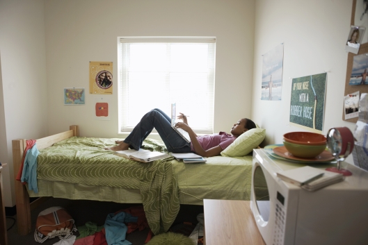 A college student lies on her bed in her room.