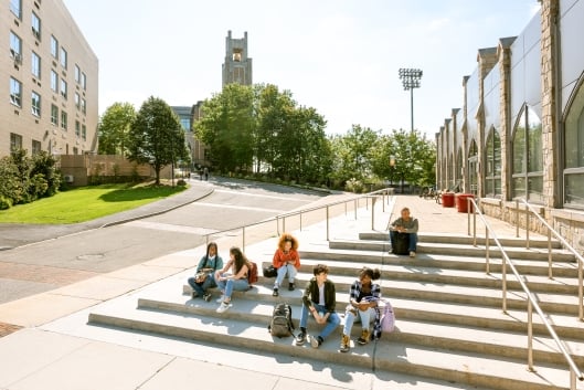 Group of university students taking a break sit on the steps of a faculty building