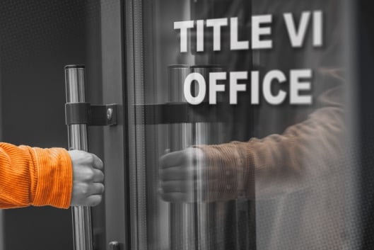 A hand reaches for the handle of a glass door labeled "Title VI Office"