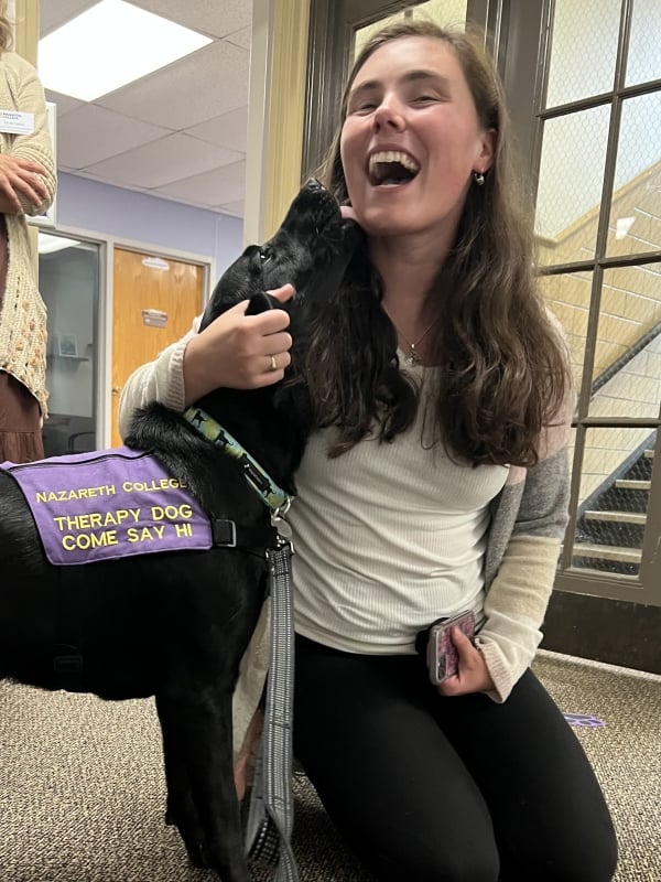 Orion the therapy dog licks a student's face.