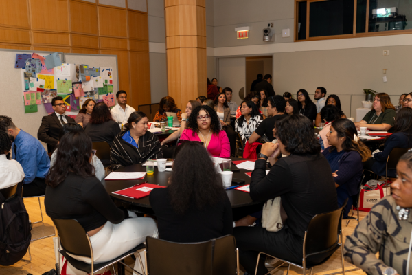 College students sit at round tables at a CREAR Futuros training event.