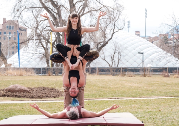 Three students practice AcroYoga on the Arapahoe Green.