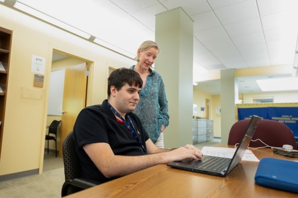 An adviser helps a student who is part of a work readiness program