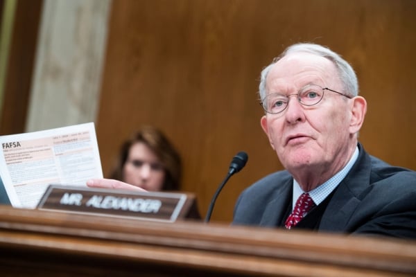 Former senator Lamar Alexander holds a paper copy of the FAFSA