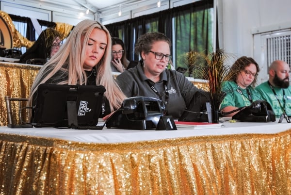 Women sit behind a table with gold cloth