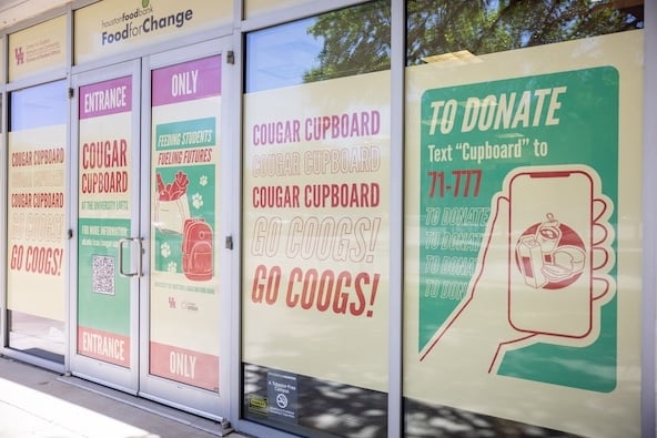 The outside of the Cougar Cupboard features bright and colorful window decals that show how to donate and school spirit messages.