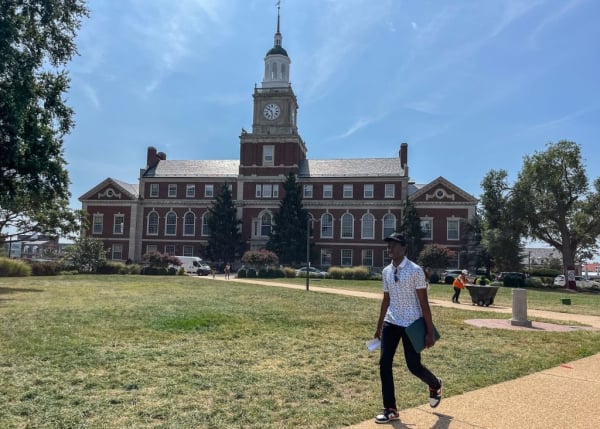 A student in front of a building on grass