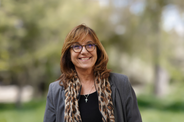 Norma Scagnoli, a light-skinned woman with auburn hair wearing glasses and an animal-print scarf.