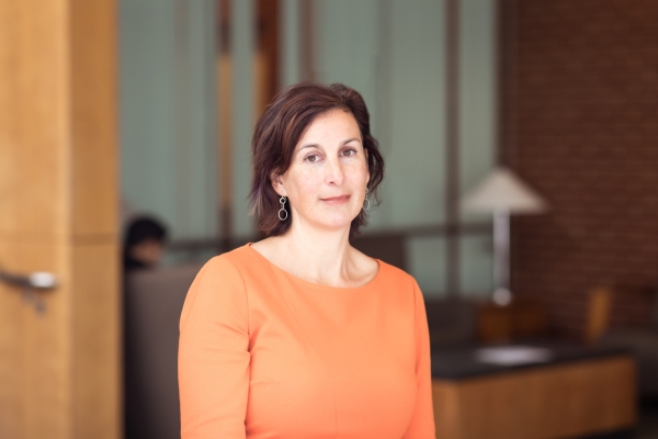 Suzanne Dove, a light-skinned woman with shoulder-length brown hair, wearing a scoop-necked orange top.