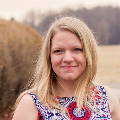 Caitlin Hayward, a light-skinned woman with blond hair who is wearing a blue and red patterned top.