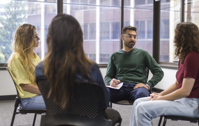 A group of college students sit in a circle during group therapy.