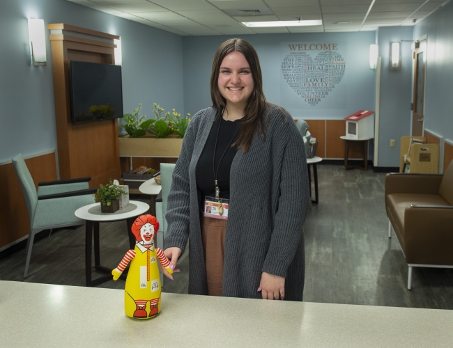 A student stands in a medical clinic next to a small Ronald McDonald toy.