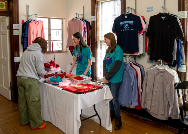 Two student employees assist a student in selecting clothing items from the free clothing store on Wittenberg University's campus.