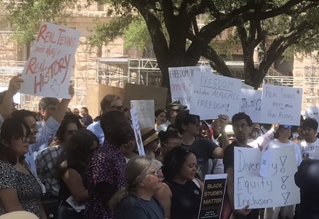 Dozens of people demonstrate holding up signs