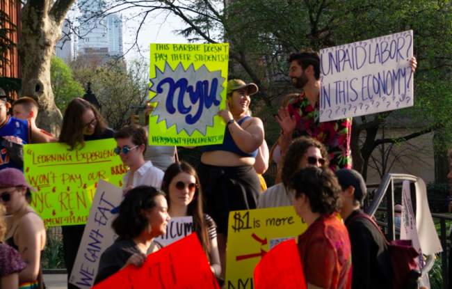 New York social work students hold up signs asking their universities to compensate them for fieldwork.