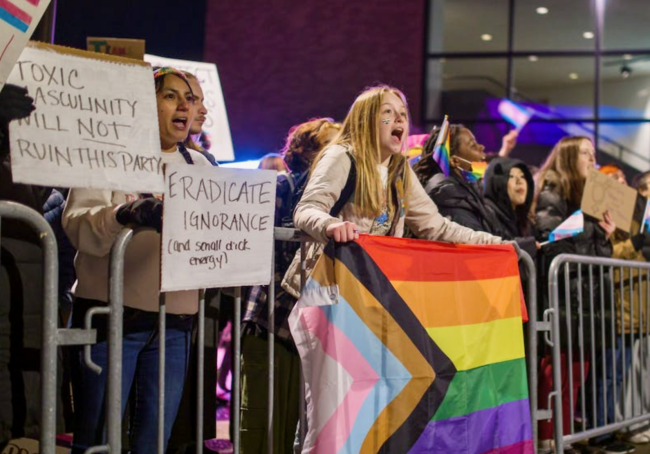 Protesters at the University of Buffalo, including one holding up a pride flag, demonstrate outside of a Michael Knowles appearance on campus.