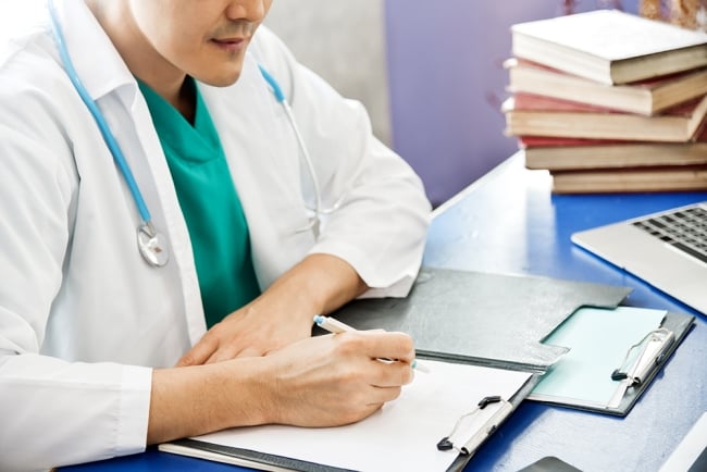 Doctor writing on clipboard