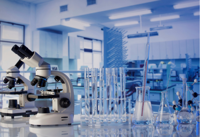 A scientific laboratory, featuring a microscope in the foreground and lots of glassware in the background.