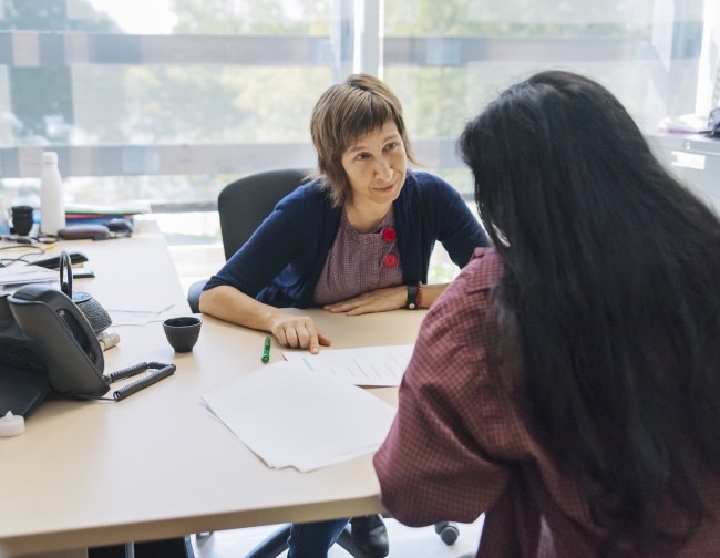 A college counselor meets with a young female student in her office.