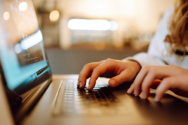 Female hands working on a laptop, close up.