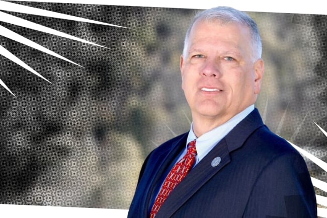 Michael Laliberte, a light-skinned man with white hair wearing a business suit and red tie.