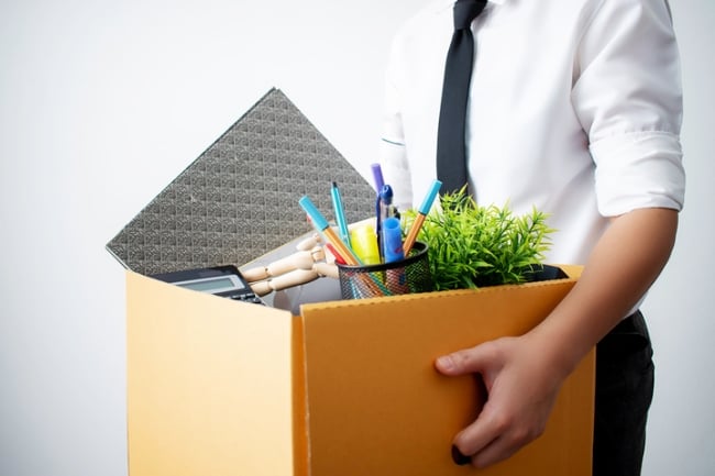 An office worker carries a box of their belongings