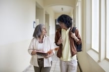 Female professor talks with student in a hallway