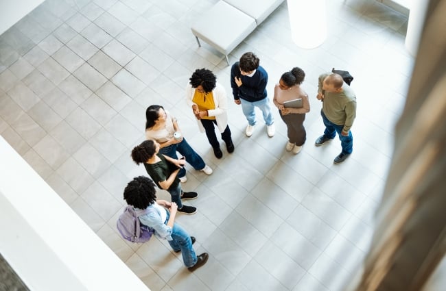 Group of diverse students gathered around a professor and talking