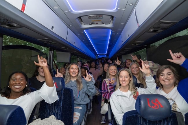 The interior of a bus full of smiling high school students heading to University of South Alabama for a tour.