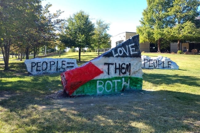 A photo of three rocks, two of which read "people = people," one of which says "love them both" over the Palestinian flag.