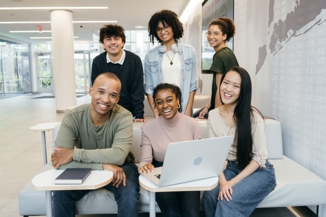 Students of different nationalities with a book and computer or standing