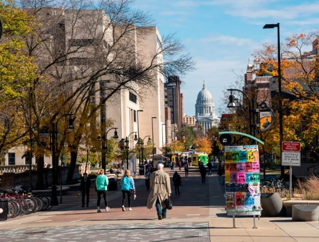 A street with people walking and a domed building on the horizon