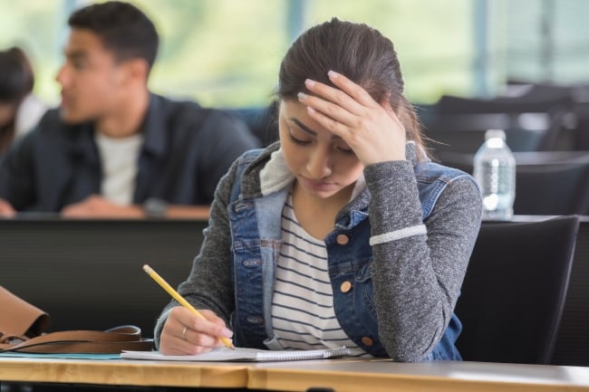 A stressed-out student works at her desk.