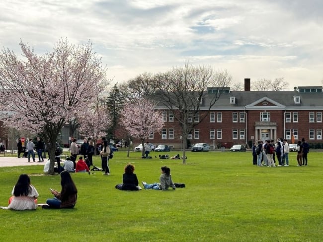 Students sit on a lawn outside academic buildings at Nassau Community College.