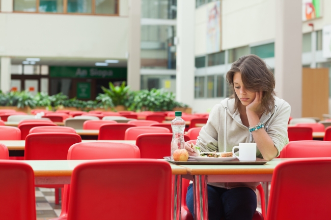 A student sits alone in a dining facility