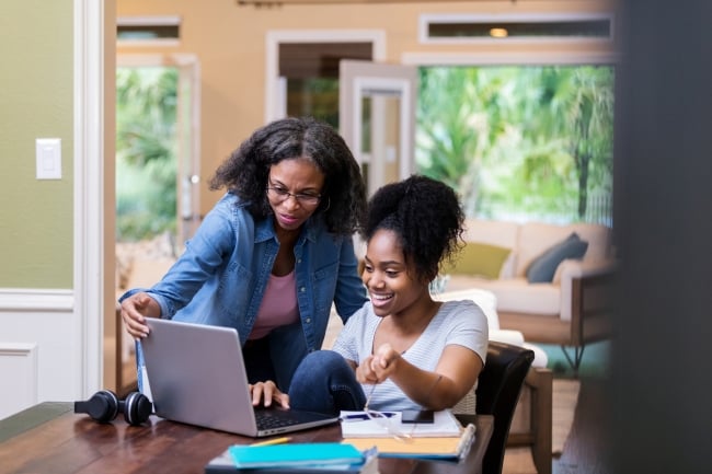 A mom and daughter work together on a laptop