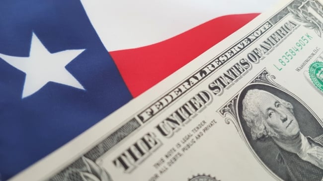 A dollar bill on top of a Texas flag.