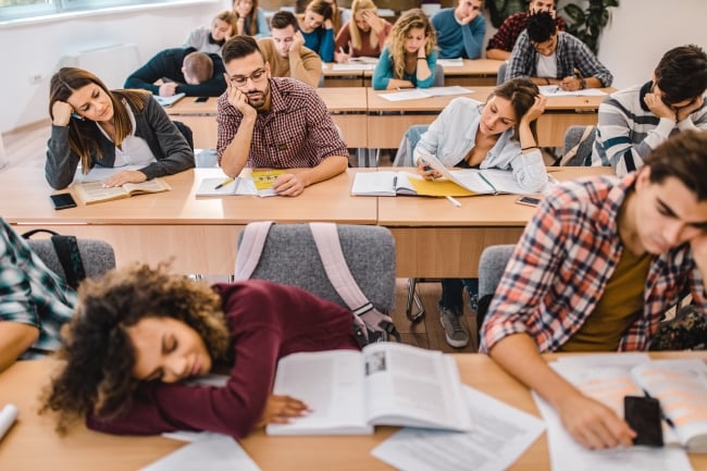 Large group of tired college students in the classroom.