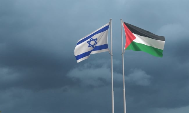 Israeli and Palestinian flags wave on two flagpoles next to one another.