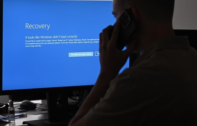 A person talking on the phone in front of a blue error screen