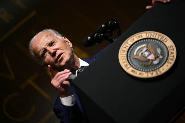 President Biden, at an angle, speaks from a podium with the presidential seal