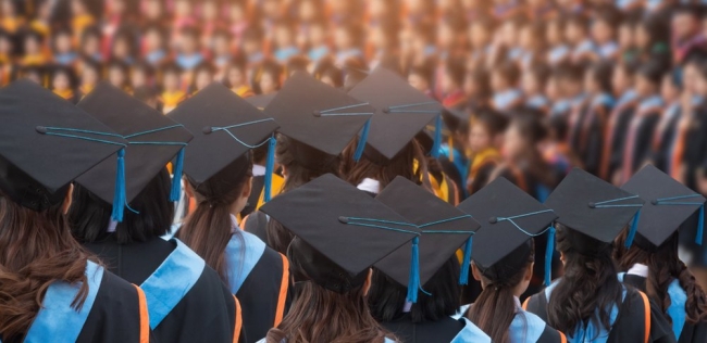 Graduates wearing commencement regalia with their backs to the camera