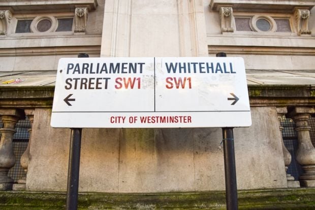 Two London street signs point toward government buildings