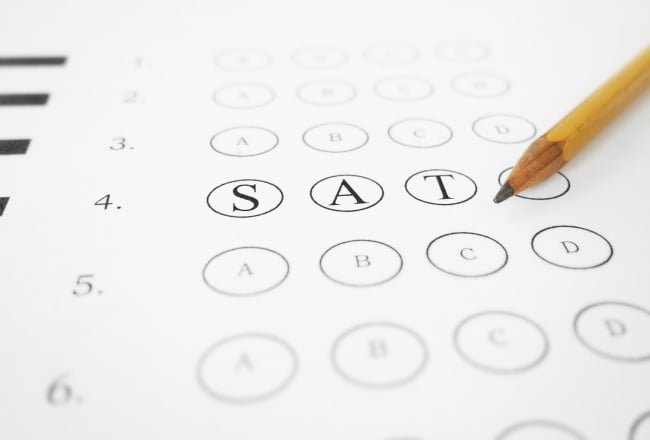 A multiple-choice test answer sheet with the letters "S," "A" and "T" prominently featured in bubbles (instead of the traditional "A," "B," "C," and "D" choices). A sharpened No. 2 pencil lies on top of the answer sheet.