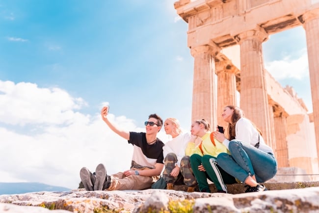 Young people taking a selfie sitting on the steps of the Acropolis